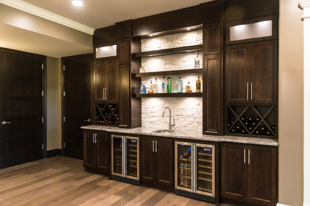 Expansive contemporary single-wall wet bar in Chicago with a submerged sink, shaker cabinets, dark wood cabinets, granite worktops, white splashback, stone tiled splashback and light hardwood flooring.