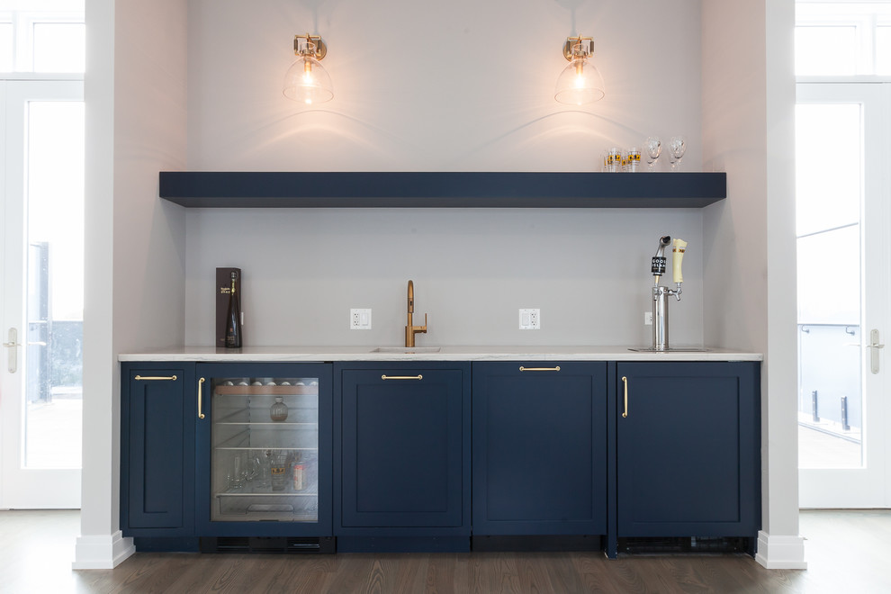 Imagen de bar en casa con fregadero actual con fregadero bajoencimera, armarios estilo shaker, puertas de armario azules, suelo de madera oscura y suelo marrón