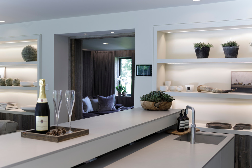 Photo of a medium sized contemporary galley wet bar in Cheshire with a built-in sink, flat-panel cabinets, medium wood cabinets, concrete worktops, white splashback, ceramic splashback, ceramic flooring and grey floors.