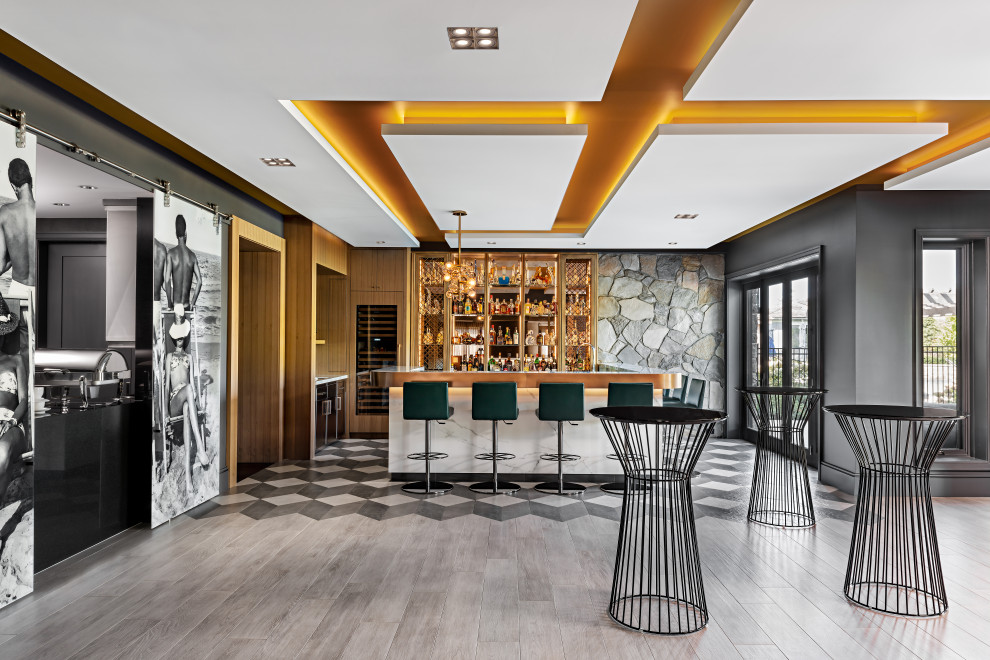 Immagine di un grande bancone bar design con ante di vetro, ante in legno chiaro, top in marmo, pavimento con piastrelle in ceramica, top bianco e pavimento grigio
