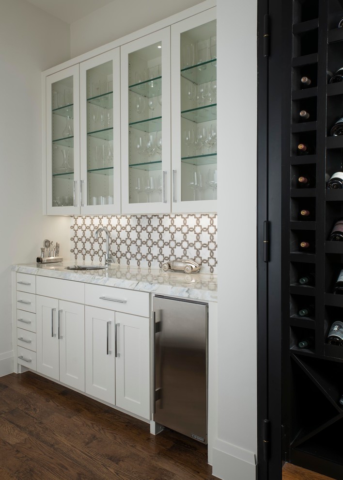 Transitional single-wall medium tone wood floor and brown floor wet bar photo in Dallas with an undermount sink, shaker cabinets, white cabinets, white backsplash and white countertops
