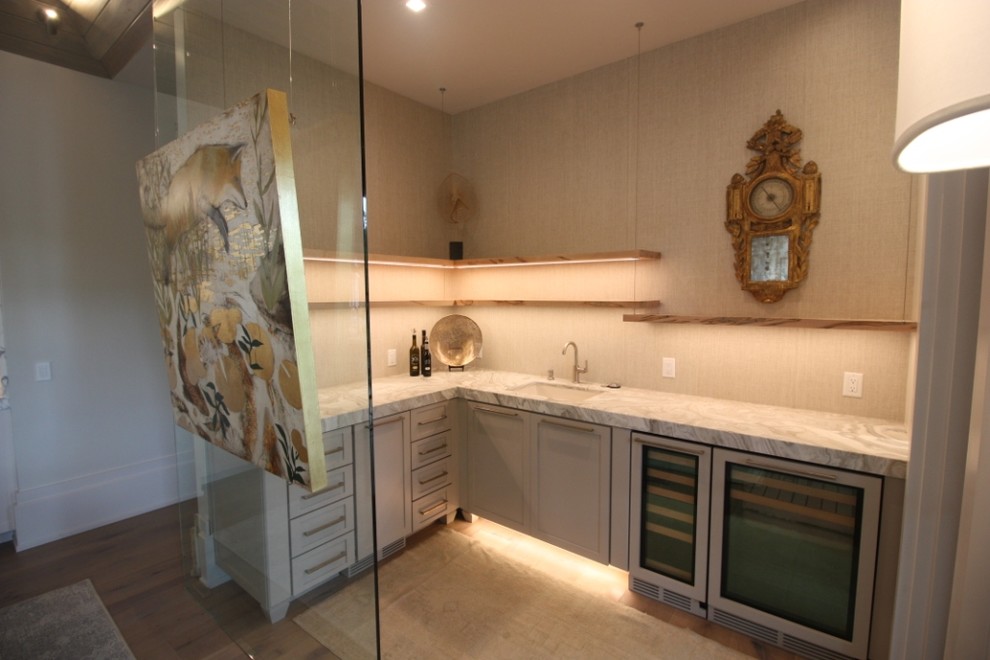Modern inredning av en mellanstor beige l-formad beige hemmabar med vask, med en undermonterad diskho, luckor med infälld panel, beige skåp, granitbänkskiva, beige stänkskydd, mellanmörkt trägolv och brunt golv