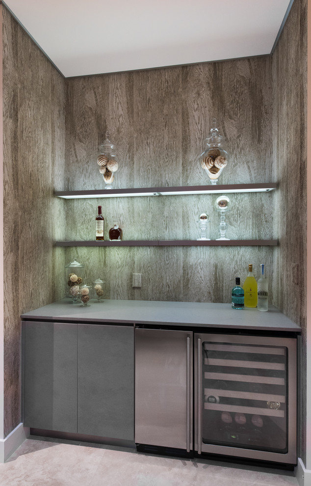 Idée de décoration pour un petit bar de salon avec évier linéaire design avec un placard à porte plane, des portes de placard grises, un plan de travail en quartz modifié et un sol en travertin.