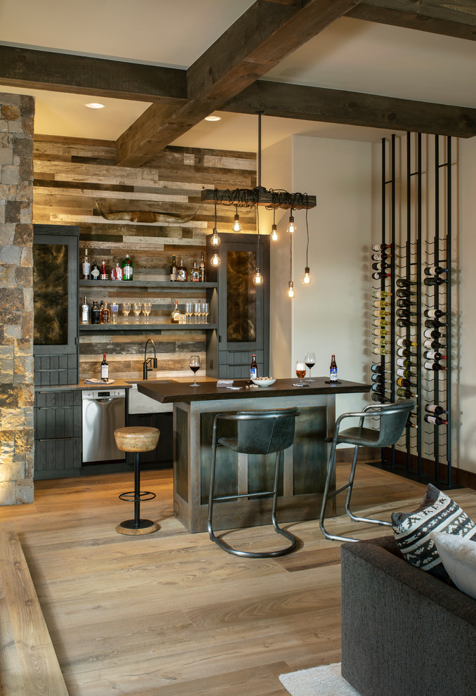 Diseño de bar en casa con barra de bar rural con armarios abiertos, salpicadero de madera, suelo de madera clara y encimeras negras