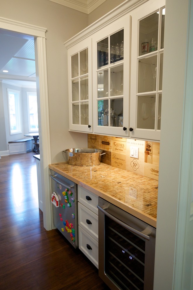 Example of a mid-sized cottage galley medium tone wood floor and brown floor wet bar design in Chicago with shaker cabinets, white cabinets, beige backsplash and beige countertops