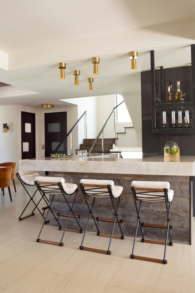 Cette image montre un bar de salon design avec des tabourets, un placard sans porte, une crédence noire et un sol beige.