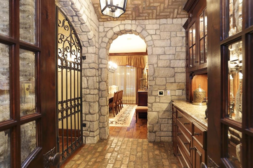 Inspiration for a large traditional single-wall wet bar in Houston with raised-panel cabinets, dark wood cabinets, brick flooring and granite worktops.