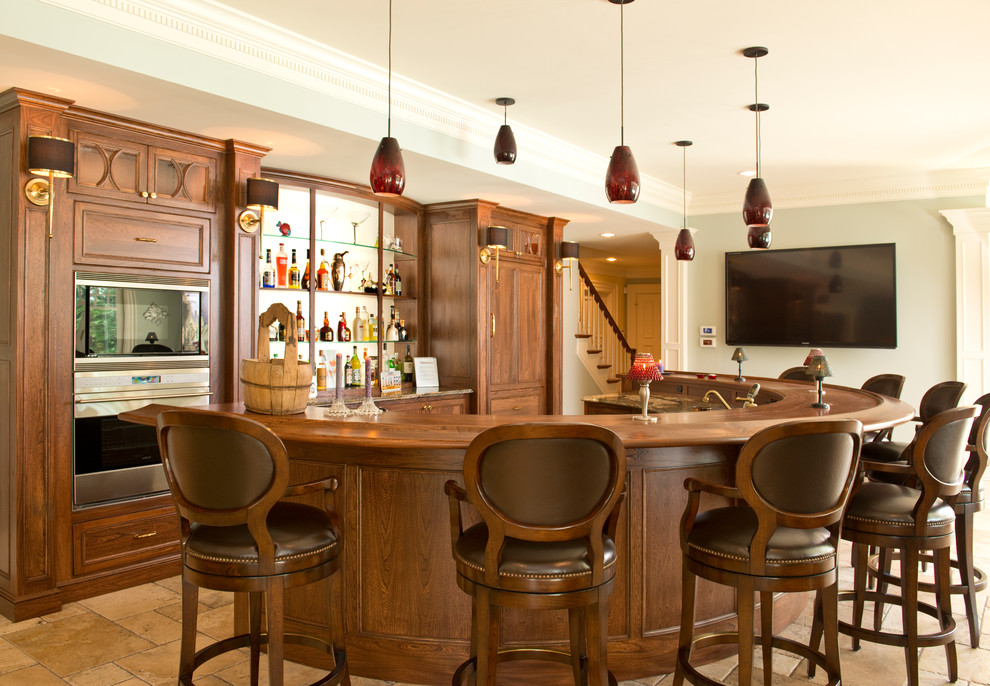 Modelo de bar en casa con barra de bar clásico con armarios con paneles empotrados, puertas de armario de madera en tonos medios, encimera de madera, suelo de piedra caliza y encimeras marrones
