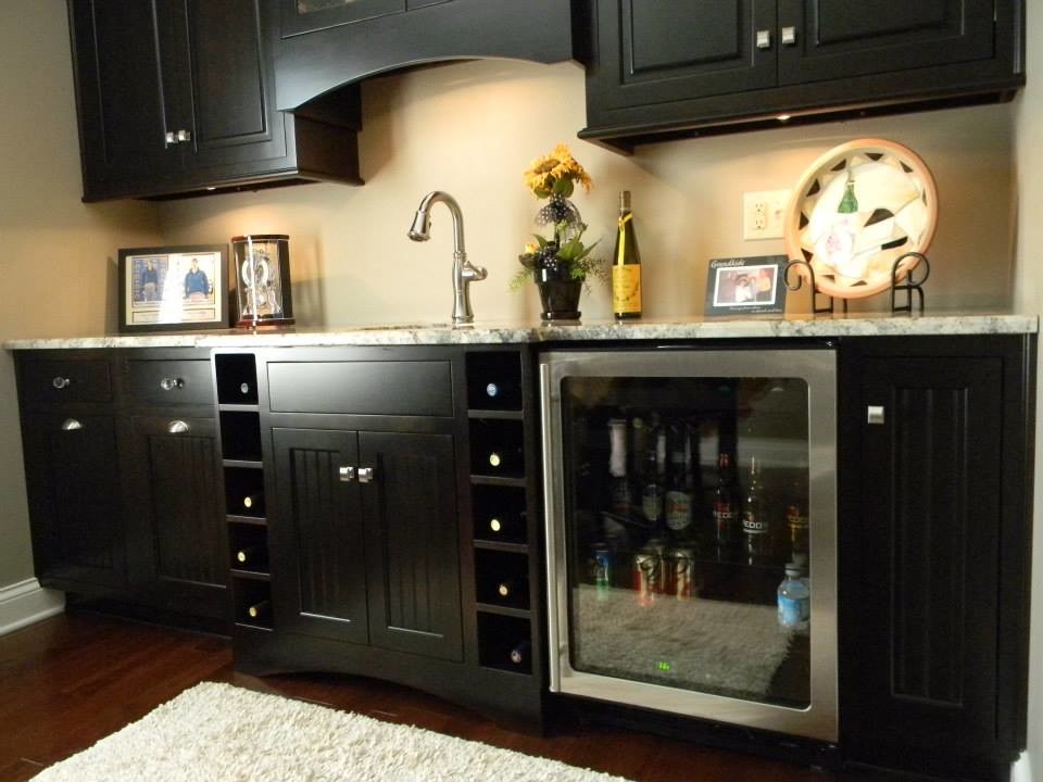 Imagen de bar en casa con fregadero lineal clásico renovado pequeño con puertas de armario negras, suelo de madera oscura y encimera de granito