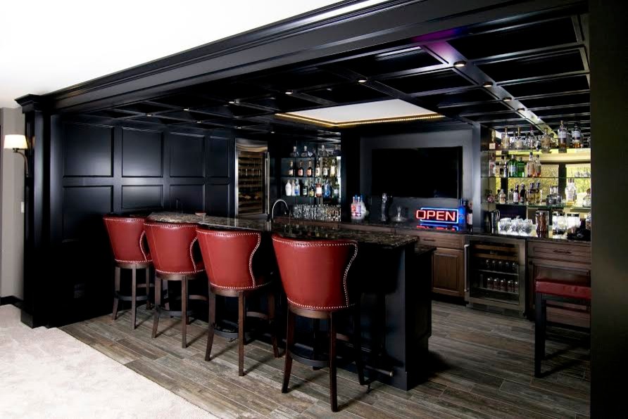Exemple d'un grand bar de salon parallèle industriel en bois foncé avec des tabourets, un placard avec porte à panneau encastré, un plan de travail en granite, une crédence miroir, parquet foncé et un sol gris.