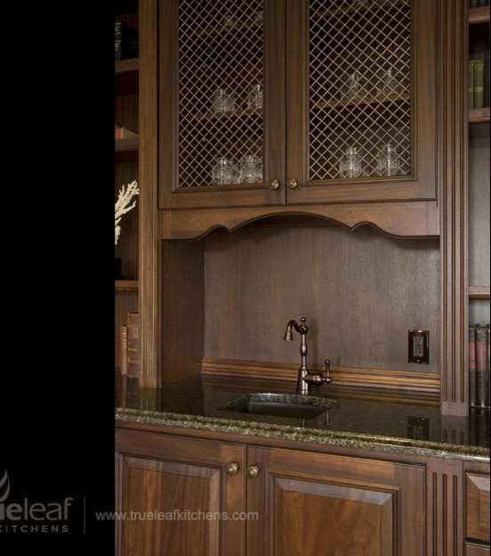 Immagine di un piccolo angolo bar con lavandino chic con lavello sottopiano, ante con bugna sagomata, ante in legno bruno e top in granito