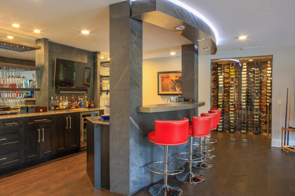 Large trendy galley medium tone wood floor seated home bar photo in New York with shaker cabinets, black cabinets, quartz countertops and mirror backsplash