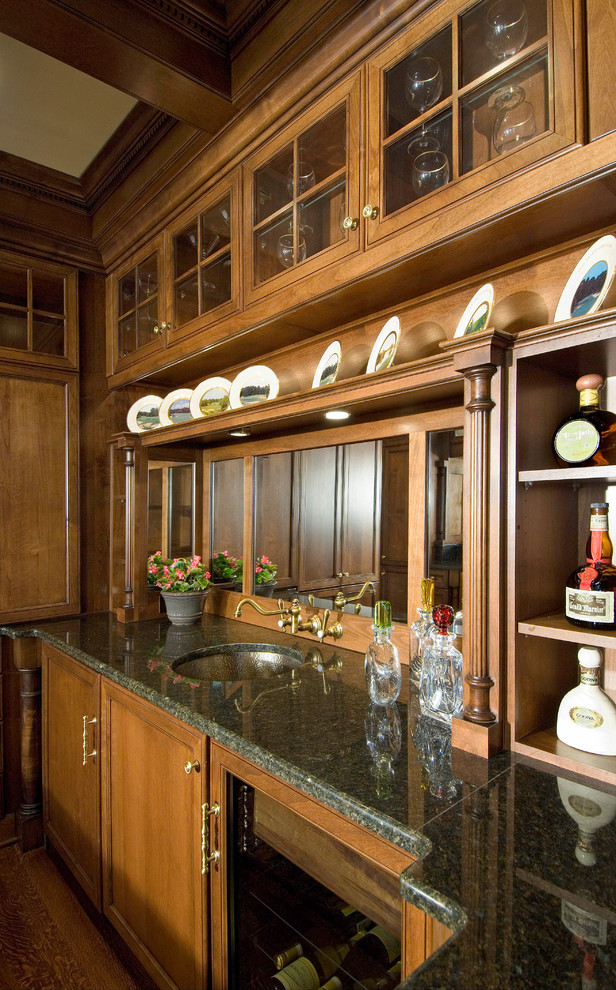 Diseño de bar en casa tradicional con suelo de madera en tonos medios, fregadero bajoencimera, armarios con paneles empotrados, puertas de armario de madera oscura y salpicadero con efecto espejo
