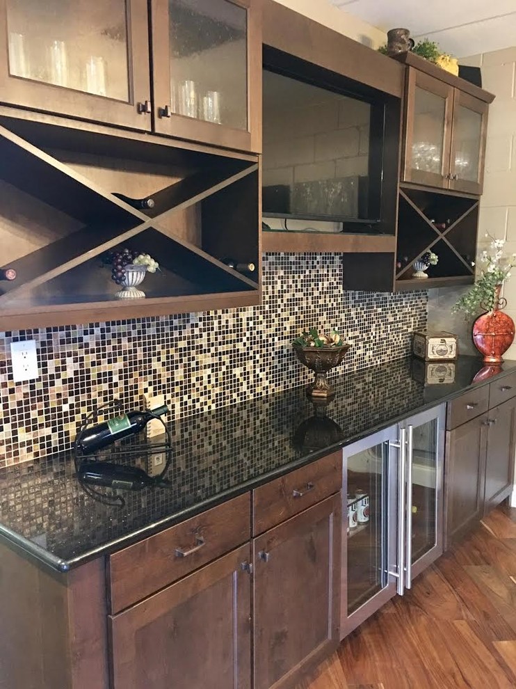 Inspiration for a large transitional single-wall medium tone wood floor and brown floor wet bar remodel in Austin with no sink, shaker cabinets, dark wood cabinets, granite countertops, multicolored backsplash and glass tile backsplash