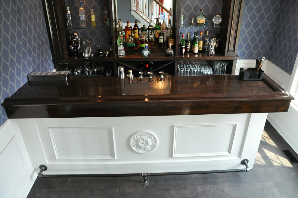 Cette image montre un grand bar de salon parallèle design en bois foncé avec des tabourets, un placard sans porte et un plan de travail en bois.