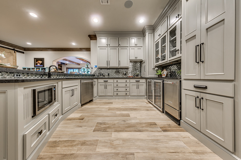 Inspiration for a mid-sized transitional galley light wood floor kitchen remodel in Oklahoma City with recessed-panel cabinets, gray cabinets, granite countertops and mirror backsplash
