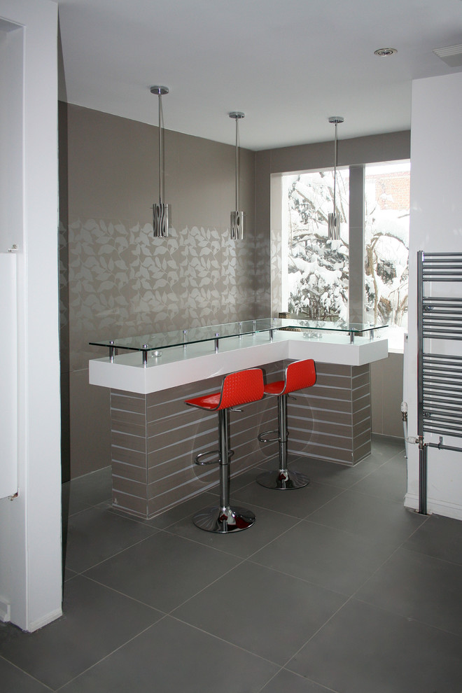 Cette photo montre un bar de salon moderne en L de taille moyenne avec des tabourets, un plan de travail en verre et un sol en carrelage de porcelaine.