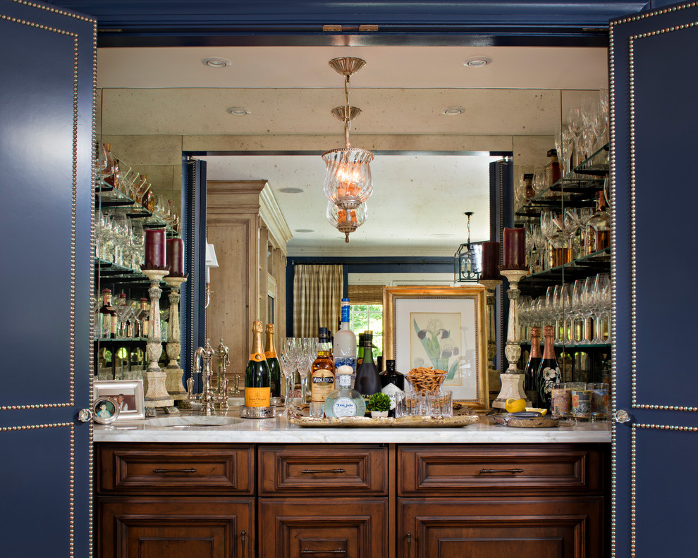 Esempio di un piccolo angolo bar con lavandino classico con lavello sottopiano, ante in legno bruno, top in marmo, paraspruzzi a specchio e ante con bugna sagomata