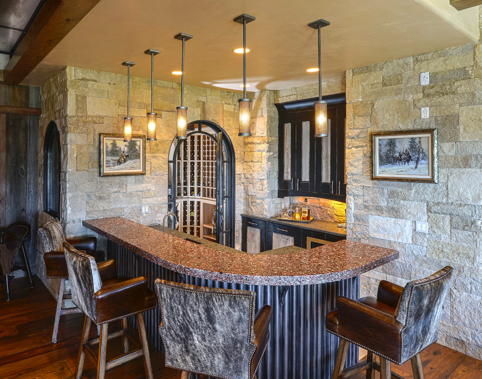 Large mountain style l-shaped dark wood floor and brown floor seated home bar photo in Other with a drop-in sink, recessed-panel cabinets, distressed cabinets, granite countertops, beige backsplash and stone tile backsplash