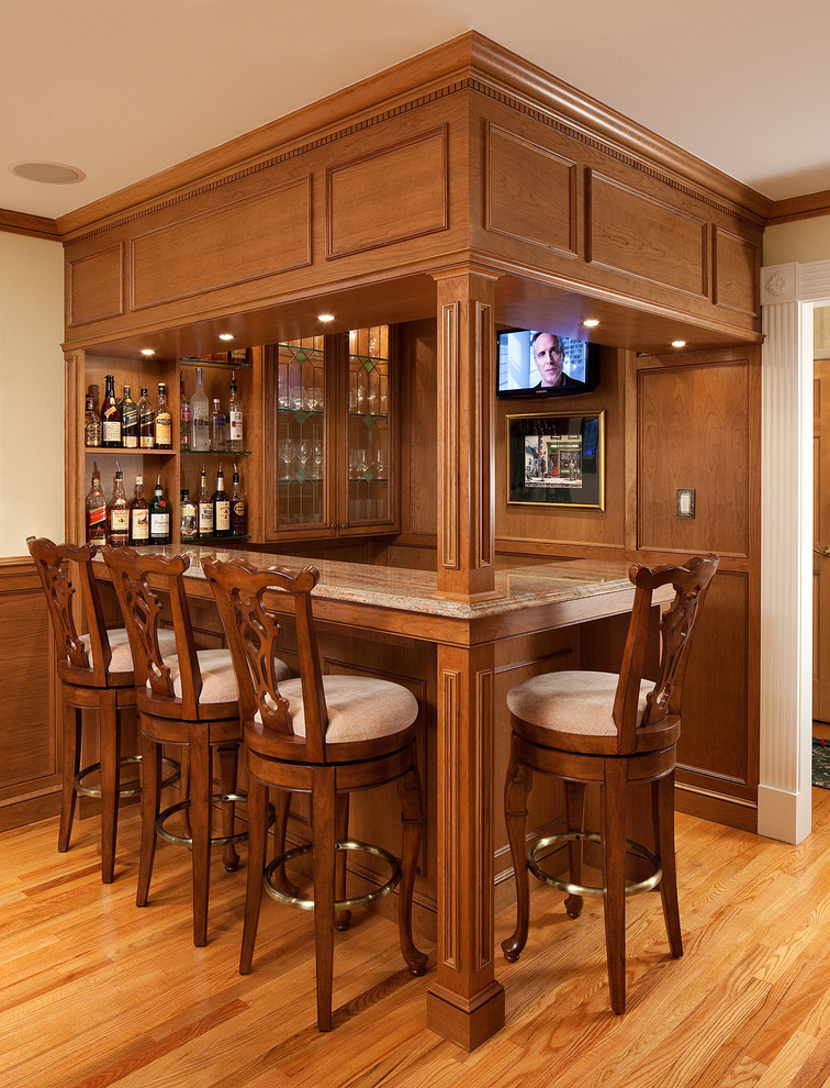 Cette image montre un bar de salon avec évier traditionnel en L et bois brun de taille moyenne avec un placard à porte vitrée, un plan de travail en granite, un sol en bois brun et une crédence marron.