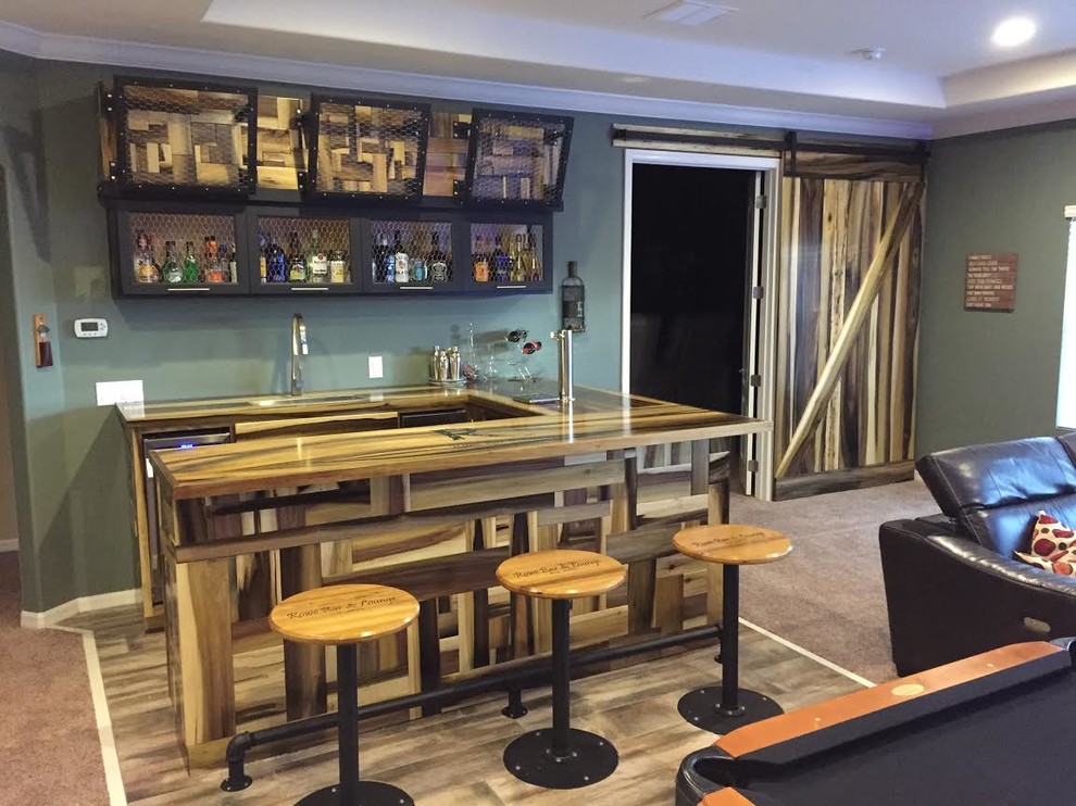 Réalisation d'un grand bar de salon parallèle chalet en bois foncé avec des tabourets, un placard avec porte à panneau encastré, un plan de travail en bois, une crédence verte et un sol en bois brun.