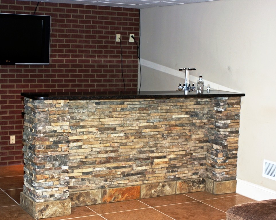 Example of a small urban galley porcelain tile and orange floor wet bar design in Atlanta with a drop-in sink, recessed-panel cabinets, granite countertops, red backsplash, brick backsplash and black countertops