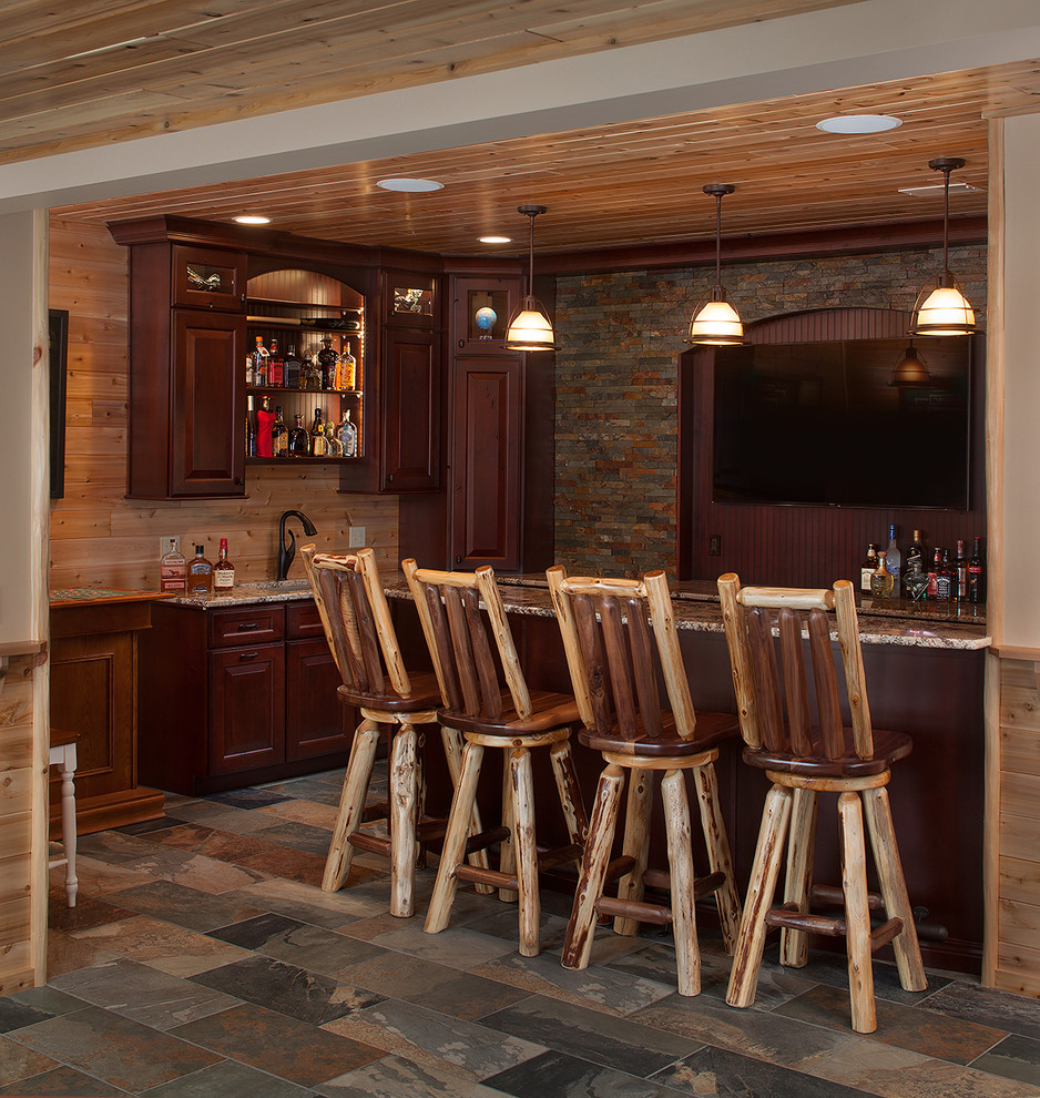 Exempel på en liten rustik l-formad hemmabar med stolar, med en undermonterad diskho, luckor med infälld panel, granitbänkskiva, grått stänkskydd, stänkskydd i stenkakel, skiffergolv och skåp i mörkt trä