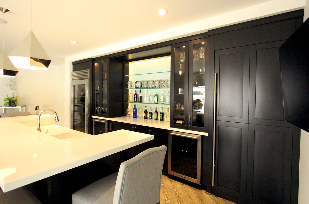 This is an example of a large modern single-wall breakfast bar in Other with a submerged sink, shaker cabinets, dark wood cabinets, engineered stone countertops, white splashback, glass sheet splashback, medium hardwood flooring and brown floors.