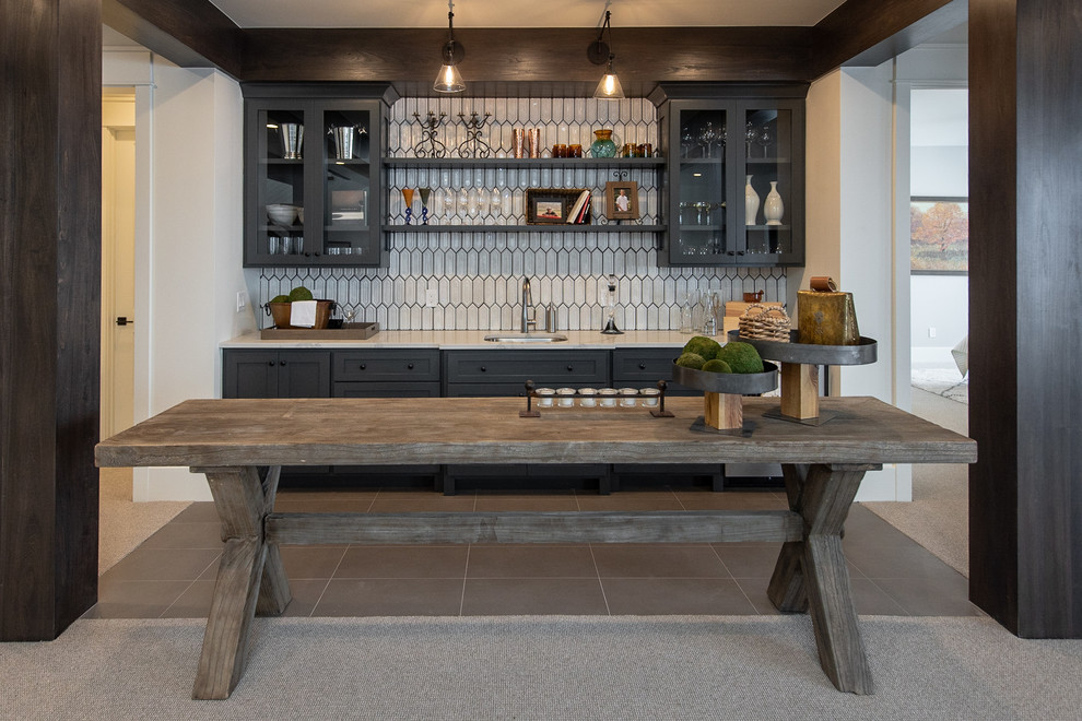 This is an example of a rustic wet bar in Salt Lake City with a submerged sink, glass-front cabinets, black cabinets, white splashback, grey floors and white worktops.