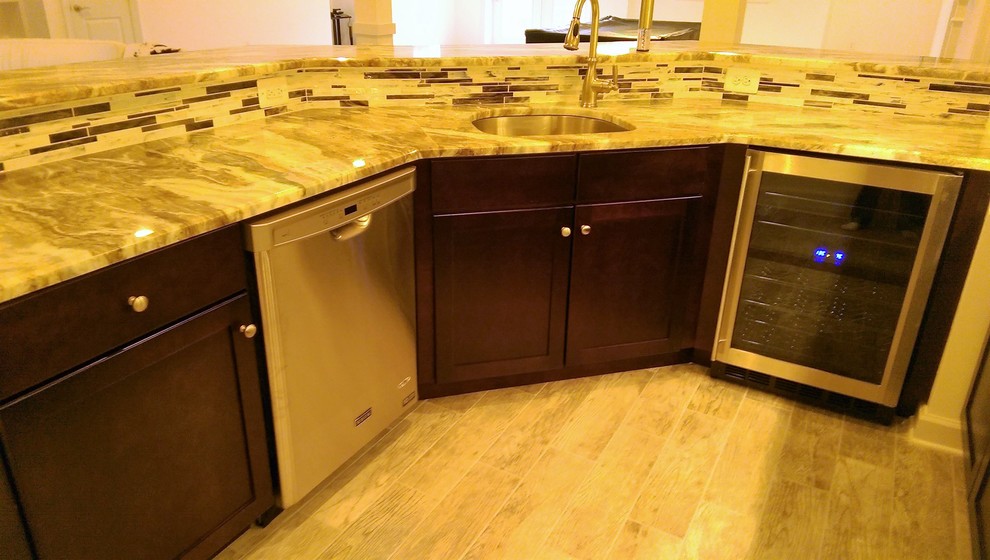 Photo of a large traditional u-shaped breakfast bar in DC Metro with a submerged sink, recessed-panel cabinets, dark wood cabinets, marble worktops, multi-coloured splashback, glass tiled splashback, porcelain flooring and beige floors.