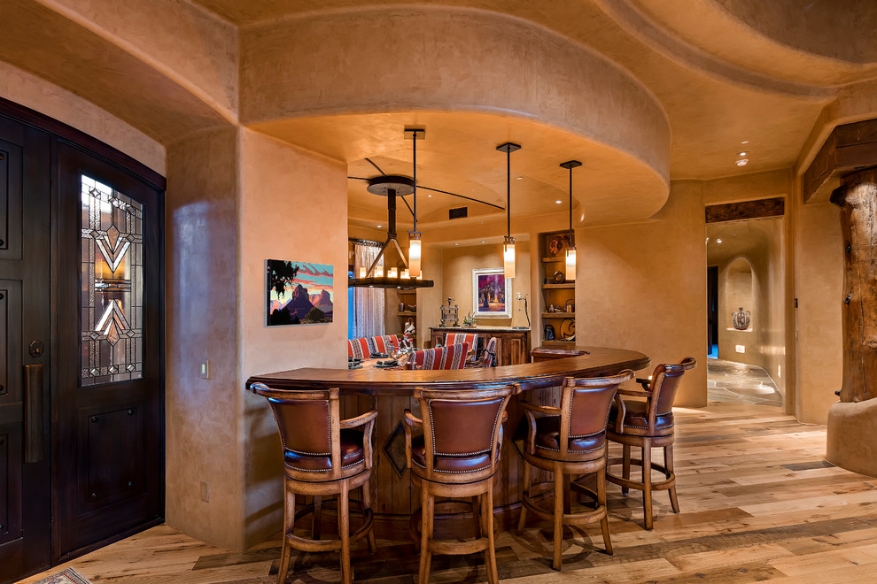 Cette photo montre un bar de salon sud-ouest américain avec un placard avec porte à panneau surélevé, un plan de travail en bois et un sol en bois brun.