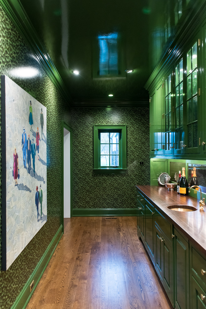 Large elegant single-wall brown floor and dark wood floor wet bar photo in Philadelphia with an undermount sink, raised-panel cabinets, green cabinets, wood countertops, mirror backsplash and brown countertops