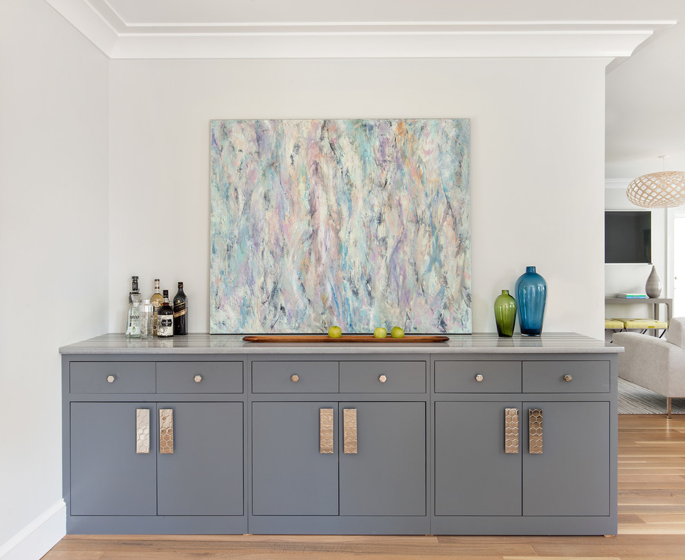 Inspiration for a transitional single-wall medium tone wood floor home bar remodel in New York with flat-panel cabinets and gray cabinets