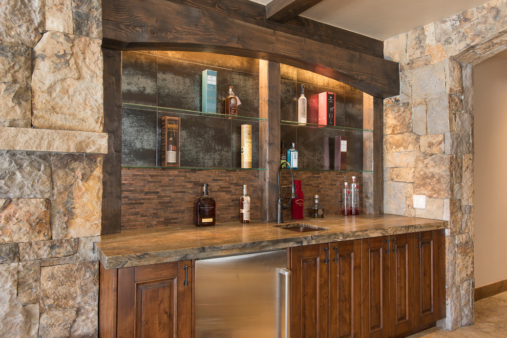 Inspiration for a rustic l-shaped home bar in Denver with beaded cabinets, medium wood cabinets, granite worktops, beige splashback, medium hardwood flooring and brown floors.
