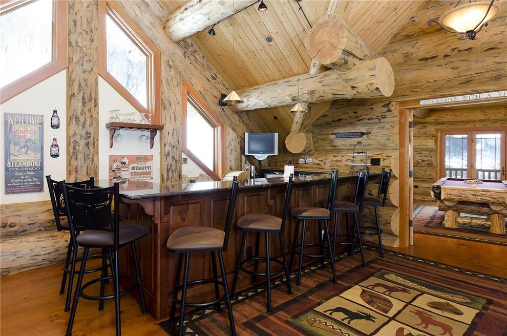 Mittelgroße Rustikale Hausbar in L-Form mit Bartheke, braunem Holzboden, dunklen Holzschränken und Granit-Arbeitsplatte in Denver