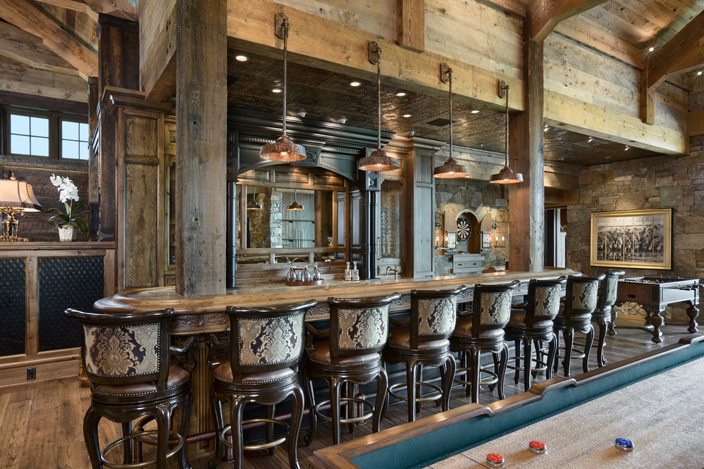 Ejemplo de bar en casa con barra de bar rural con suelo de madera oscura