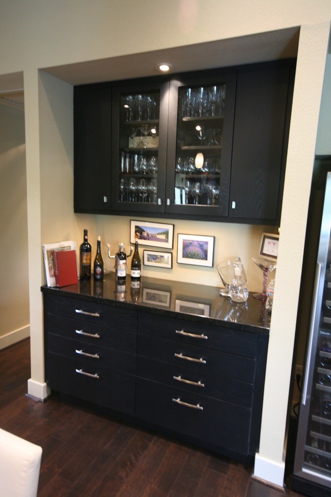 Bild på en mellanstor funkis parallell hemmabar med vask, med släta luckor, granitbänkskiva, mörkt trägolv, svarta skåp och brunt golv