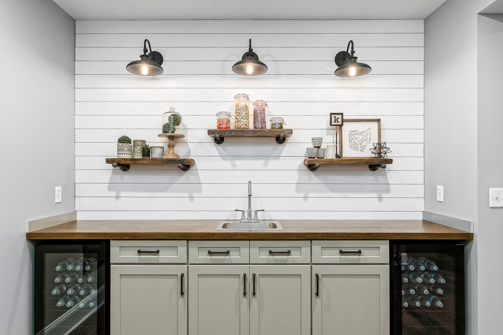 Mid-sized farmhouse single-wall medium tone wood floor and brown floor seated home bar photo in Columbus with a drop-in sink, shaker cabinets, white cabinets, wood countertops, white backsplash and wood backsplash
