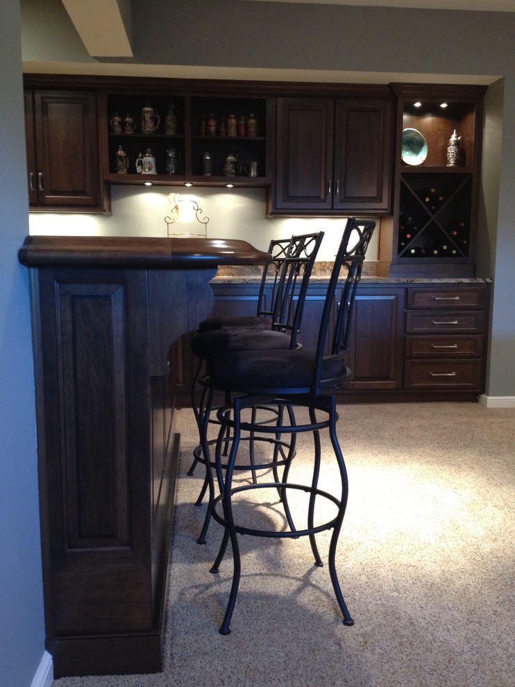 Example of a large classic l-shaped ceramic tile and brown floor seated home bar design in Indianapolis with an undermount sink, raised-panel cabinets, dark wood cabinets and granite countertops