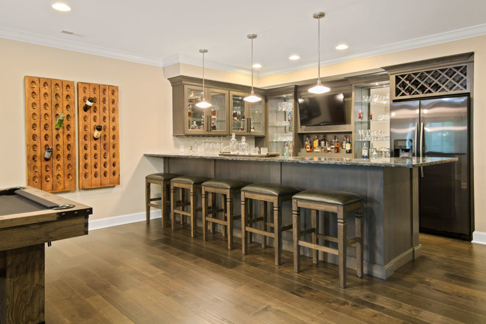 Inspiration pour un grand bar de salon avec évier linéaire traditionnel en bois brun avec un placard sans porte, un plan de travail en granite et parquet foncé.