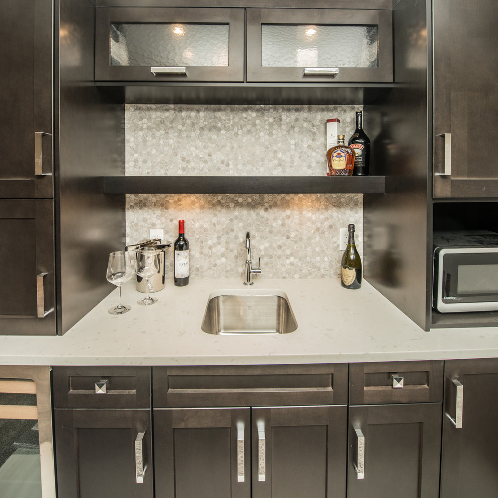 Inspiration for a mid-sized transitional single-wall wet bar remodel in Calgary with an undermount sink, shaker cabinets, dark wood cabinets, gray backsplash, mosaic tile backsplash and quartz countertops