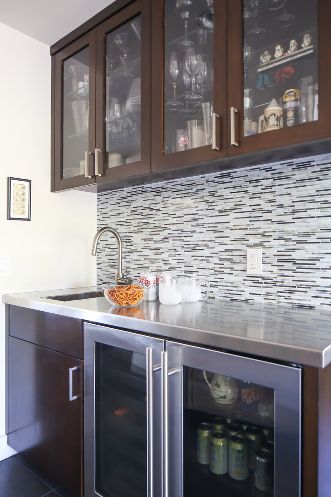 Small trendy single-wall porcelain tile wet bar photo in Orange County with an undermount sink, glass-front cabinets, dark wood cabinets, stainless steel countertops, multicolored backsplash and glass tile backsplash