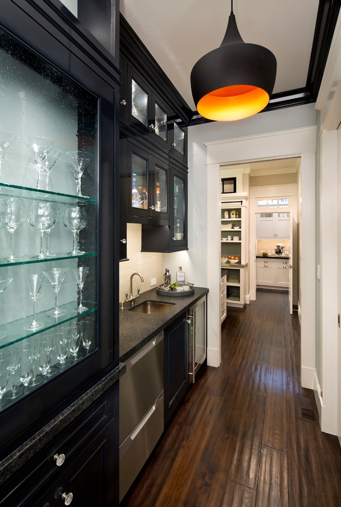 Wet bar - mid-sized traditional single-wall dark wood floor wet bar idea in San Francisco with an undermount sink, glass-front cabinets, black cabinets, granite countertops, white backsplash and subway tile backsplash