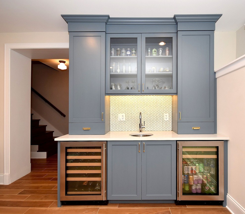 Inspiration for a classic home bar in Chicago with a submerged sink, shaker cabinets, blue cabinets, engineered stone countertops, white splashback, ceramic splashback, porcelain flooring, brown floors and white worktops.