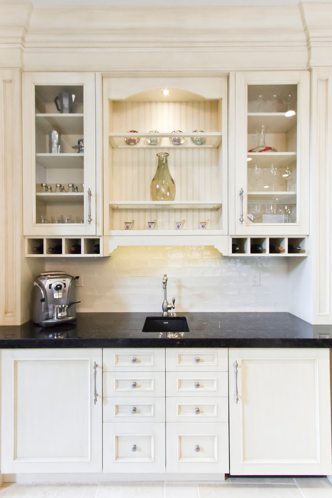 This is an example of a medium sized traditional galley breakfast bar in Toronto with a built-in sink, raised-panel cabinets, white cabinets, composite countertops, black splashback, metro tiled splashback and ceramic flooring.