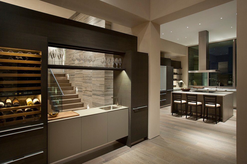 Immagine di un grande angolo bar con lavandino minimalista con lavello sottopiano, ante lisce, ante in legno bruno e pavimento in legno massello medio