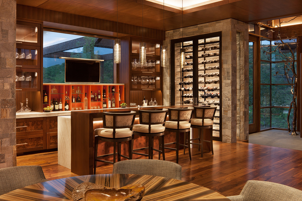 Cette image montre un très grand bar de salon chalet en bois foncé avec des tabourets, parquet foncé, un sol marron et un placard avec porte à panneau encastré.