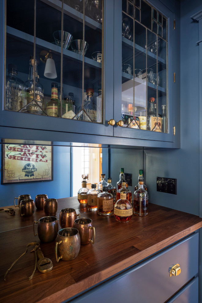 Immagine di un piccolo angolo bar classico con ante blu, top in legno, paraspruzzi a specchio, pavimento in legno massello medio, pavimento marrone e top marrone