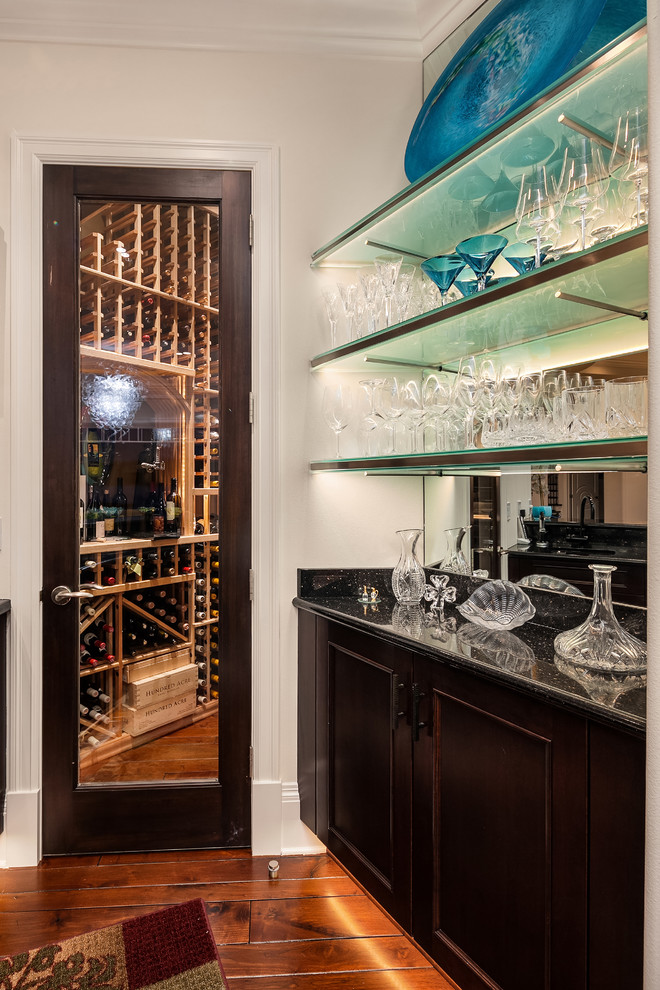 Inspiration for an expansive contemporary single-wall wet bar in Seattle with shaker cabinets, brown cabinets, granite worktops, mirror splashback, dark hardwood flooring, brown floors and black worktops.