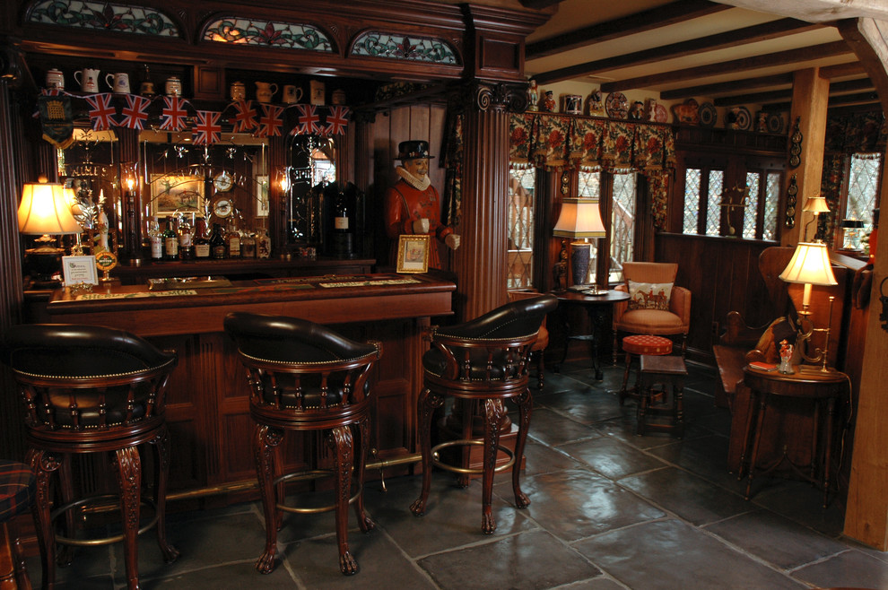 Diseño de bar en casa con barra de bar clásico grande con armarios con rebordes decorativos, puertas de armario de madera en tonos medios y suelo de pizarra